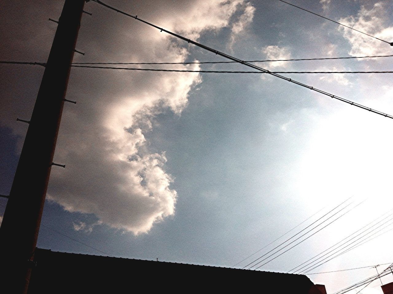 low angle view, power line, sky, cable, cloud - sky, electricity, connection, electricity pylon, power supply, built structure, architecture, silhouette, cloud, building exterior, cloudy, power cable, technology, outdoors, no people, fuel and power generation