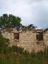 Old building by trees against sky