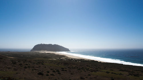 Scenic view of beach against clear blue sky