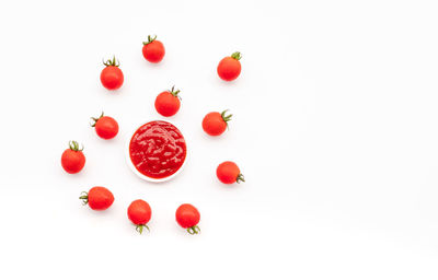 High angle view of red berries over white background