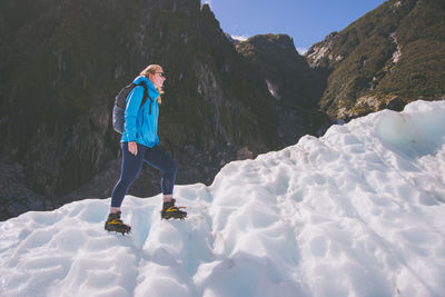 Full length side view of woman on snowcapped mountain