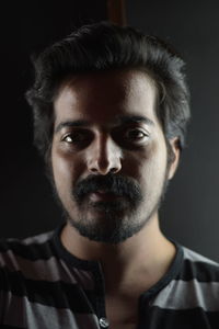 Close-up portrait of young man against black background