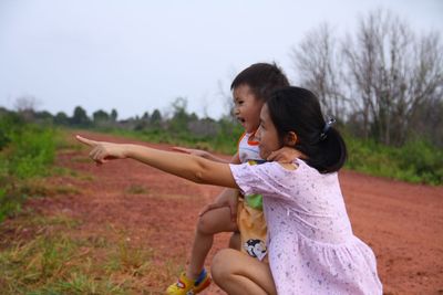 Mother and son pointing while on dirt road at field