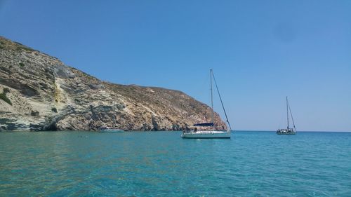 Sailboat sailing on sea against clear blue sky