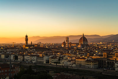 Illuminated buildings in city against sky during sunset