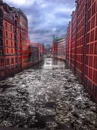 Wet sidewalk in city against sky