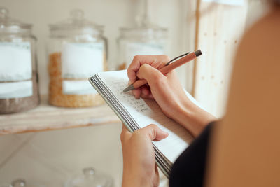 Midsection of woman writing in book