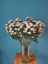 Close-up of white flower vase on table against blue sky