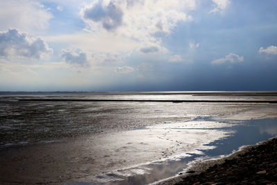 Scenic view of sea low tide against sky