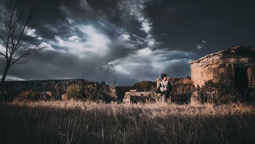 View of field against cloudy sky