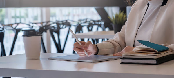 Midsection of woman reading book on table