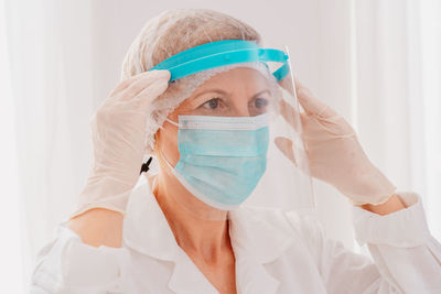 Female doctor wearing mask with face shield looking away