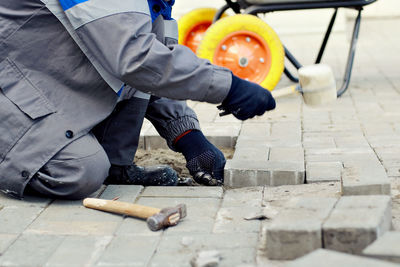 Bricklayer lays paving slabs outside. working man performs landscaping. builder lays out sidewalk