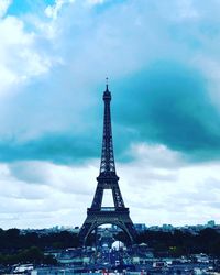 Tower in city against cloudy sky