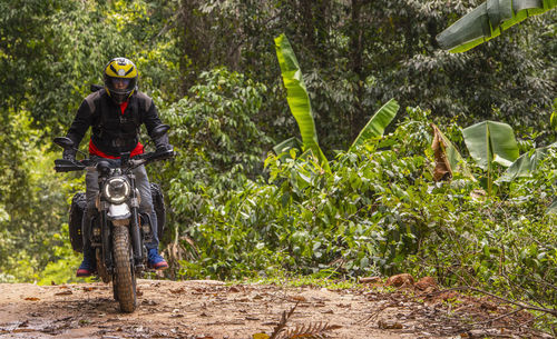 Man riding his scrambler type motorcycle through forrest