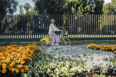 Young woman riding bicycle by fence at park