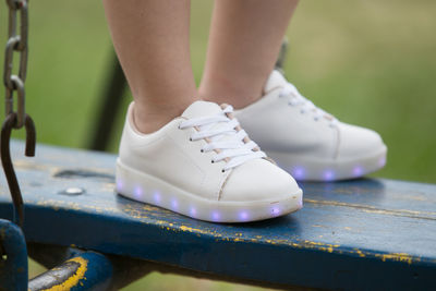 Low section of woman wearing shoes while standing on outdoor play equipment