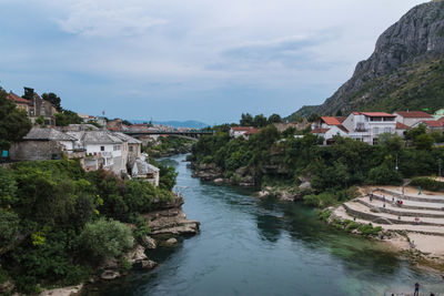 River amidst buildings and trees against sky