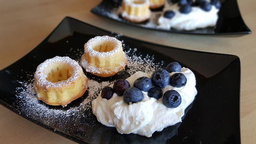 High angle view of sweet dessert on table made of little cake with cream and blueberries