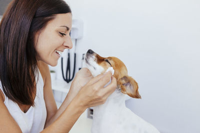 Side view of smiling veterinarian holding dog in hospital