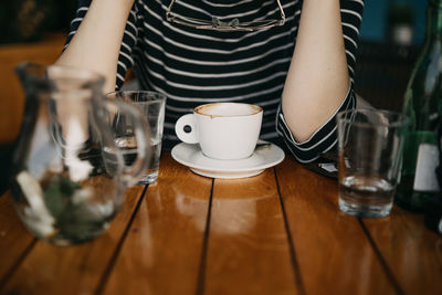 Midsection of woman having coffee at table in cafe