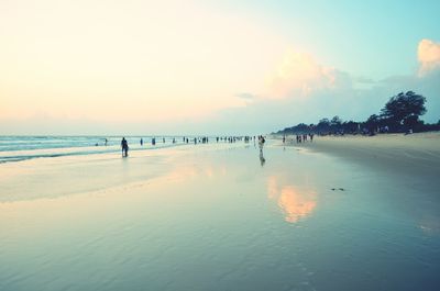 People on beach against sky during sunset