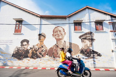 Portrait of people on street against building