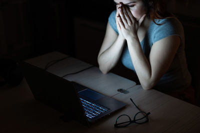 Midsection of woman using laptop at home