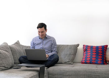 Man using laptop while sitting on sofa at home