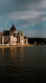 Buildings by river against sky