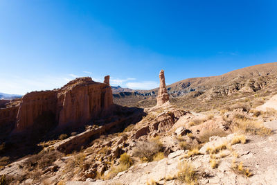 Rock formations on landscape against blue sky