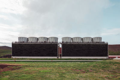 View of buildings in field against cloudy sky