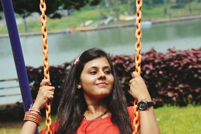 Smiling young woman swinging in park