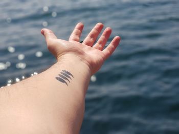 Close-up of hand with sea in background