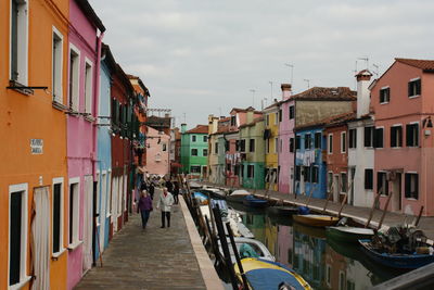 Boats in canal amidst buildings in city against sky