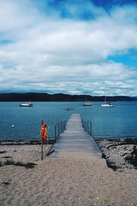 Pier on sea against cloudy sky