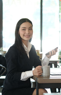 Portrait of smiling young woman with coffee