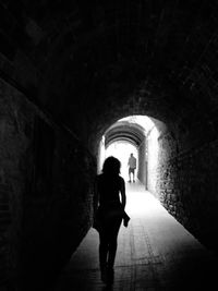 Rear view of woman walking in tunnel