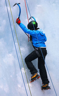 Rear view full length of woman ice climbing