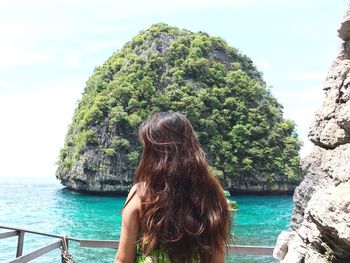 Rear view of woman standing by sea against sky