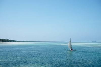 Sailboat sailing in sea against clear blue sky