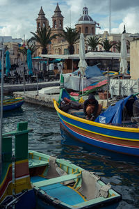 Boats moored at harbor against sky