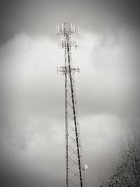 Low angle view of electricity pylon against cloudy sky