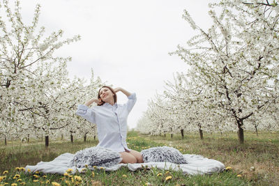 Full length of woman sitting by white flowers