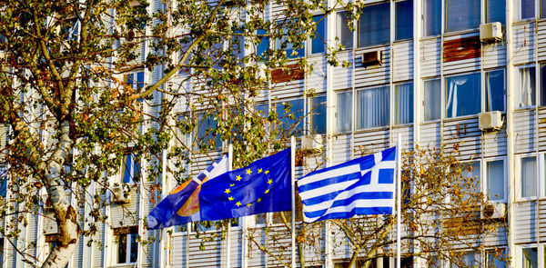 Low angle view of flags and buildings against blue sky