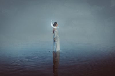 Digital composite image of woman holding sward while standing in sea against sky