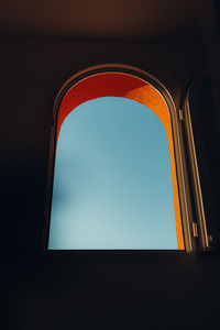 Low angle view of building against clear sky seen through window