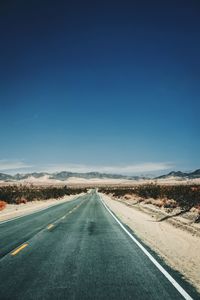 Road against clear blue sky