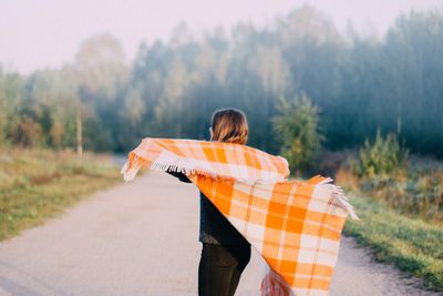 Young woman with blanket standing on road