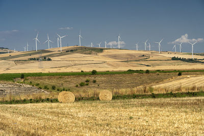 Wind turbines on field against sky